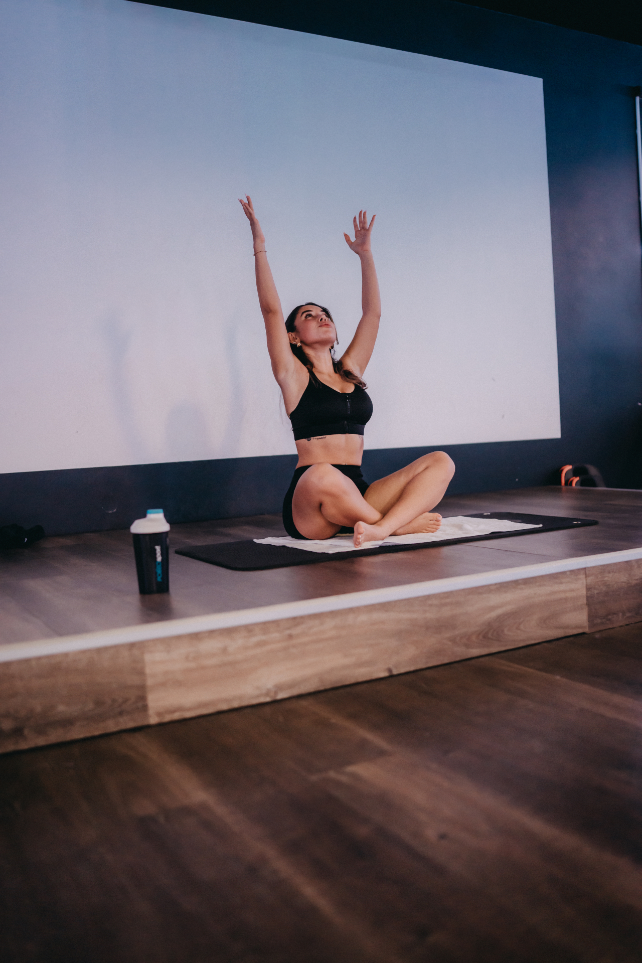 Seated stretch with arms reaching skyward on stage